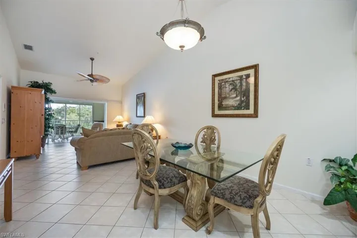 Tiled dining area featuring ceiling fan and high vaulted ceiling