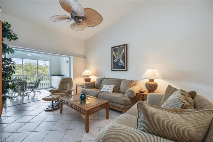 Living room with light tile patterned floors, vaulted ceiling, and ceiling fan