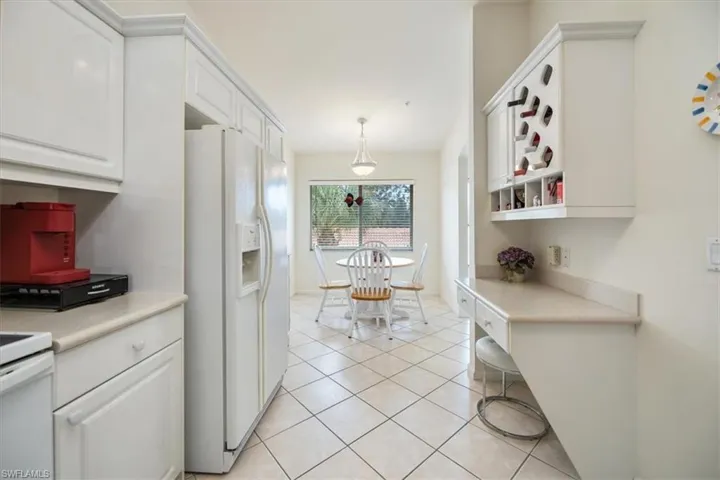 Kitchen with pendant lighting, white cabinets, white refrigerator with ice dispenser, and light tile patterned floors