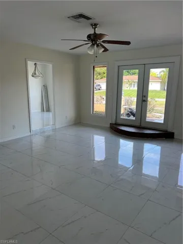 Spare room featuring light marble finish floors, a ceiling fan, and french doors