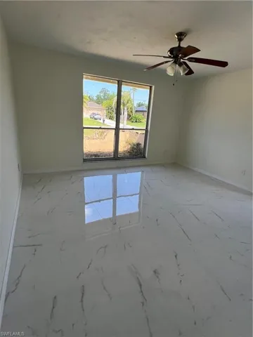 Empty room featuring light marble finish flooring and ceiling fan