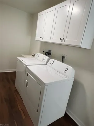 Laundry area with washer and dryer, cabinet space, and dark wood-style floors