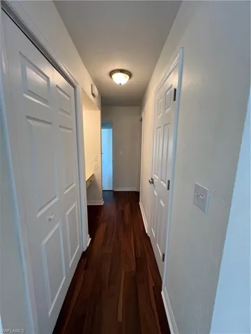 Corridor with baseboards and dark wood-style flooring