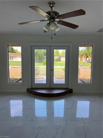 Doorway featuring light marble finish floors, french doors, and ceiling fan