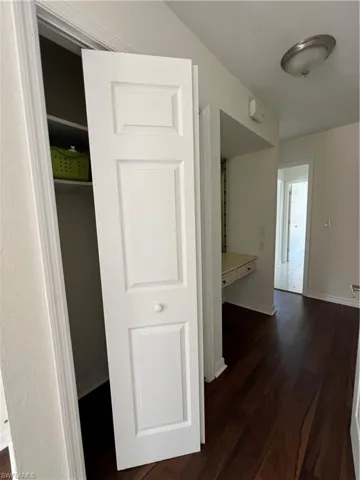 Hall with dark wood-type flooring and baseboards