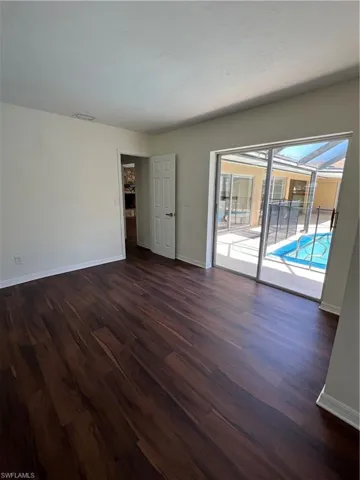 Empty room featuring dark wood finished floors and baseboards