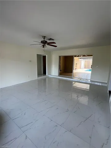 Unfurnished Living room featuring marble finish flooring and ceiling fan