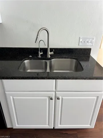Kitchen view of white cabinets and dark stone counters