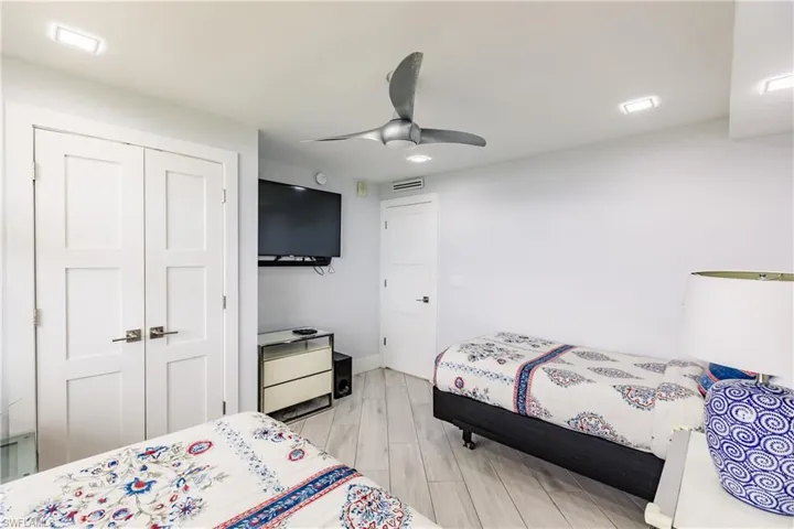 Bedroom with light wood finished floors, ceiling fan, and a closet