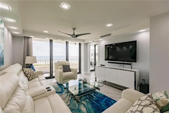 Living room with floor to ceiling windows, a ceiling fan, and light wood-style flooring