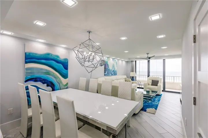 Dining area with hanging lights, expansive windows, light wood finished floors, and ceiling fan