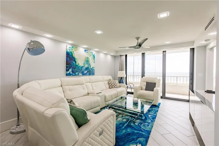 Living room featuring expansive windows, ceiling fan, light wood-style flooring, and recessed lighting