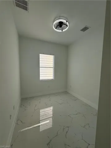 Empty room featuring light marble finish floors and baseboards