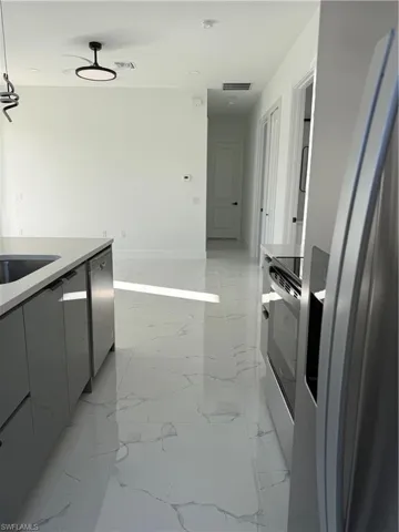 Kitchen with fridge, modern cabinets, stove, light stone counters, and light marble finish flooring