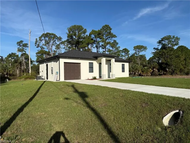 View of front facade with a front lawn, stucco siding, an attached garage, and concrete driveway