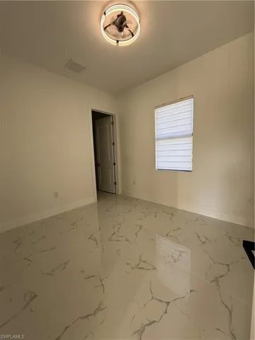 Unfurnished room featuring baseboards and light marble finish floors