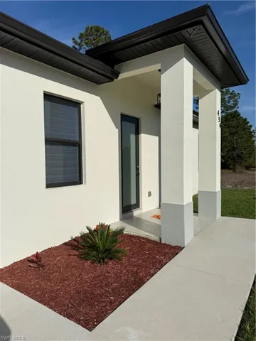 View of exterior entry featuring stucco siding and covered porch