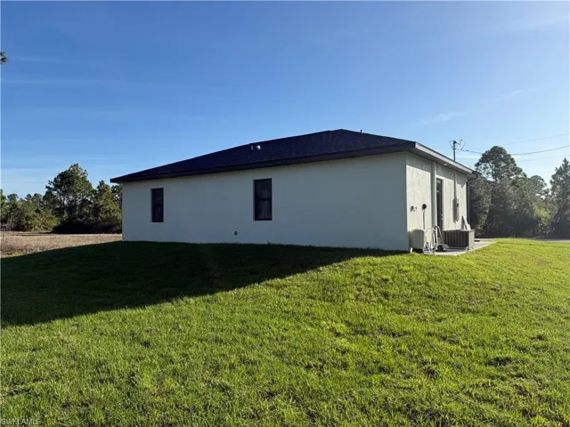 View of side of property with a yard and stucco siding