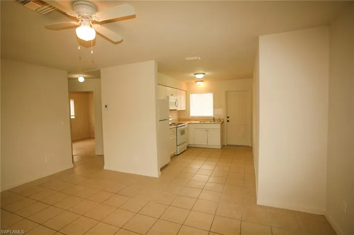 Kitchen with white cabinets, white appliances, light countertops, a ceiling fan, and light tile patterned floors