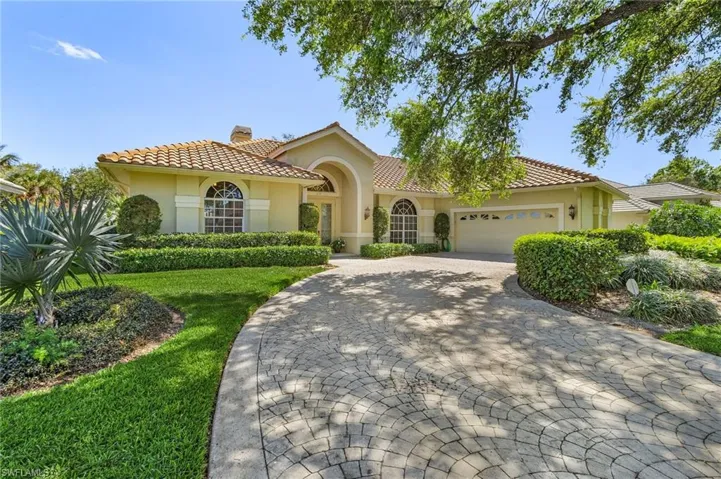 Mediterranean / spanish-style house with a chimney, stucco siding, a garage, a tiled roof, and decorative driveway