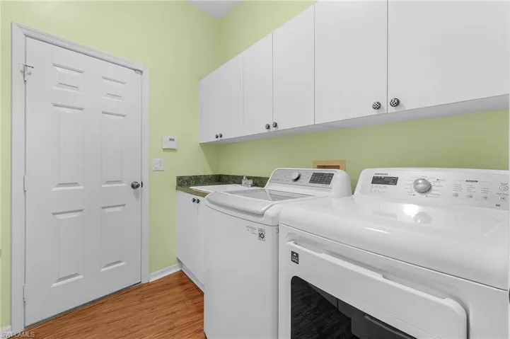 Laundry area featuring washing machine and clothes dryer, light wood-type flooring, and cabinet space