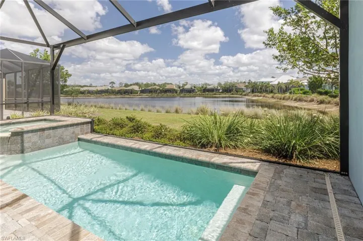 View of swimming pool featuring a water view, a pool with connected hot tub, and a lanai