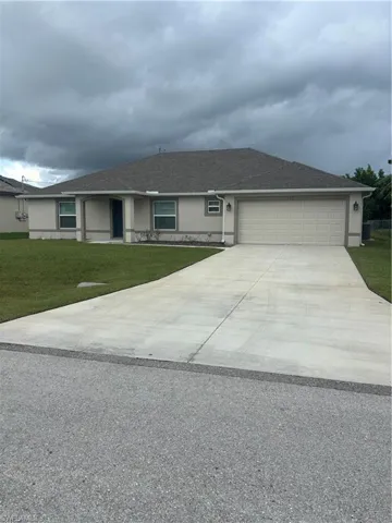 Ranch-style home featuring stucco siding, a shingled roof, driveway, a front yard, and an attached garage