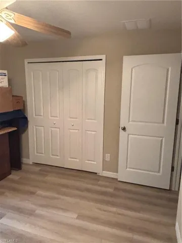 Unfurnished bedroom with a closet, light wood-style floors, and a ceiling fan