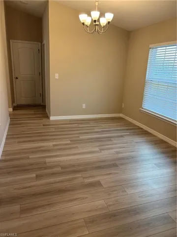 Empty room featuring a chandelier and light wood-type flooring
