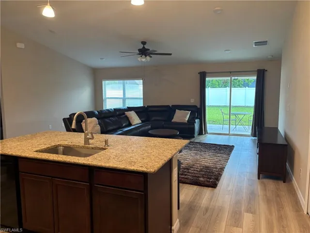 Kitchen featuring light stone countertops, healthy amount of natural light, dark brown cabinetry, light wood-type flooring, and recessed lighting