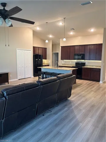 Living room with light wood-type flooring, lofted ceiling, recessed lighting, and ceiling fan
