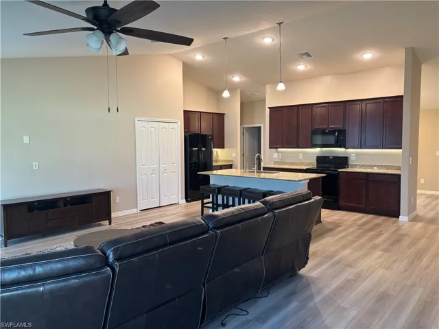 Living area with light wood-style flooring, high vaulted ceiling, ceiling fan, and recessed lighting