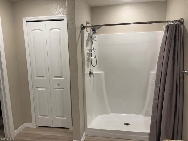 Bathroom featuring a closet, a stall shower, wood finished floors, and a textured wall