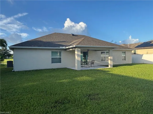 Back of house featuring stucco siding, a patio, and a lawn