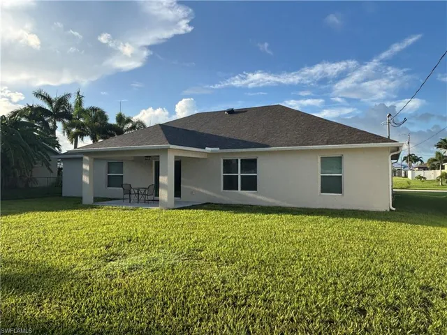 Back of property featuring stucco siding, a patio, and a lawn
