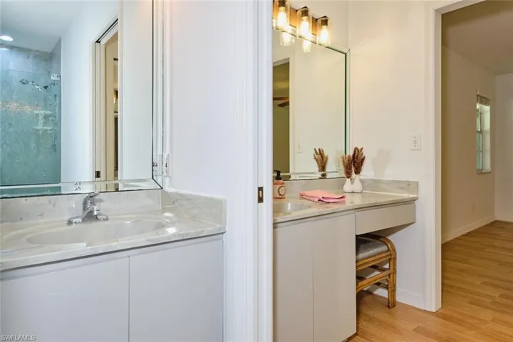 Bathroom with wood-type flooring, vanity, and tiled shower