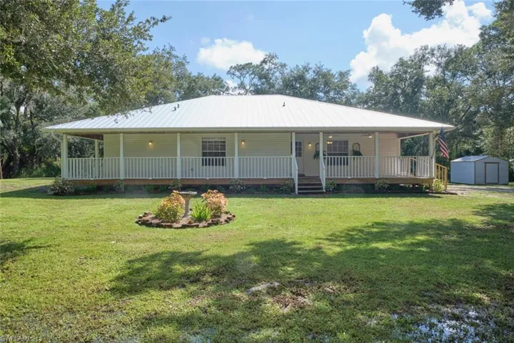 Back of house with a porch, a yard, and a storage unit