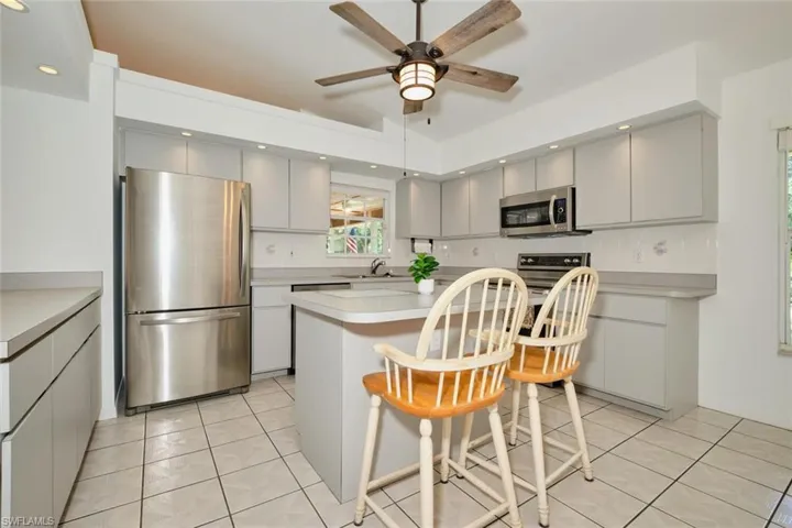 Kitchen with a breakfast bar, a center island, gray cabinetry, stainless steel appliances, and light tile patterned floors