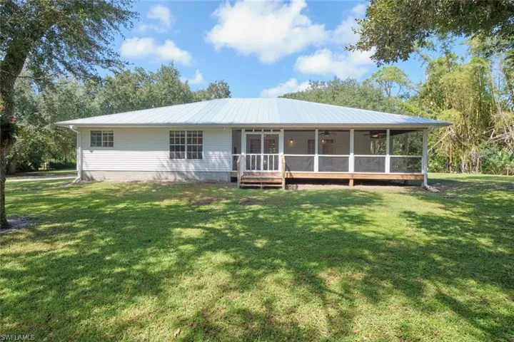 Back of house featuring a lawn and a sunroom