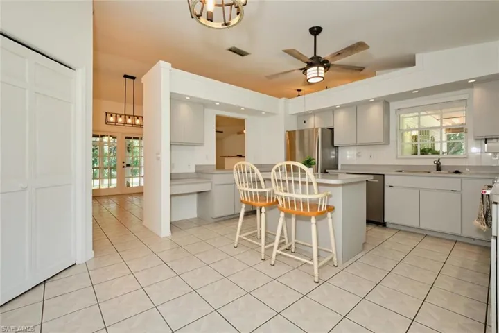 Kitchen with a breakfast bar, stainless steel refrigerator, a center island, decorative light fixtures, and sink