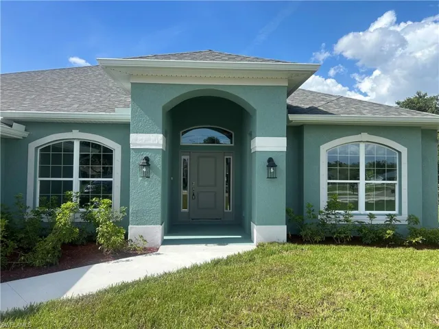 Property Entrance Featuring Roof with Shingles, Stucco Finish, and a Lawn with Floritam Sod