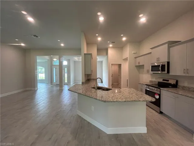 Kitchen Featuring Stainless Steel Appliances, Granite Countertops, Wood Look Ceramic Tile Flooring, a Granite Peninsula, and Recessed Lighting