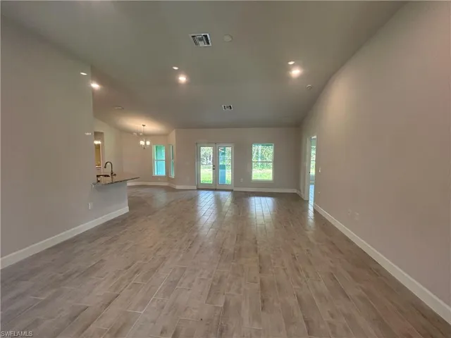 Unfurnished Living Room Featuring Wood Look Ceramic Tile Flooring, Recessed Lighting and a Vaulted Ceiling