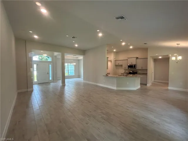 Living Room with a Chandelier, Wood Look Ceramic Tiled Floors, Recessed Lighting and Vaulted Ceiling