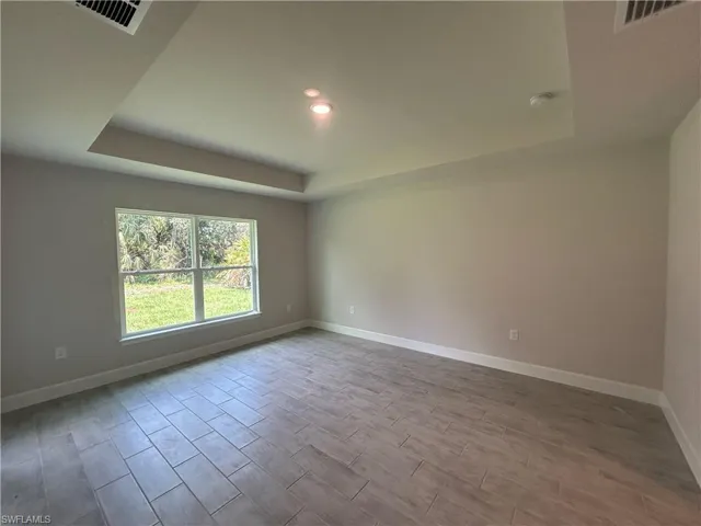 Primary Bedroom with a Tray Ceiling, Wood Look Ceramic Tiled Floor, Recessed LED Lighting, and a Smoke Detector