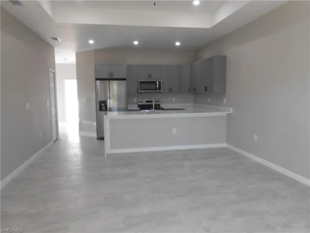 Kitchen with gray cabinetry, light countertops, recessed lighting, a peninsula, and appliances with stainless steel finishes