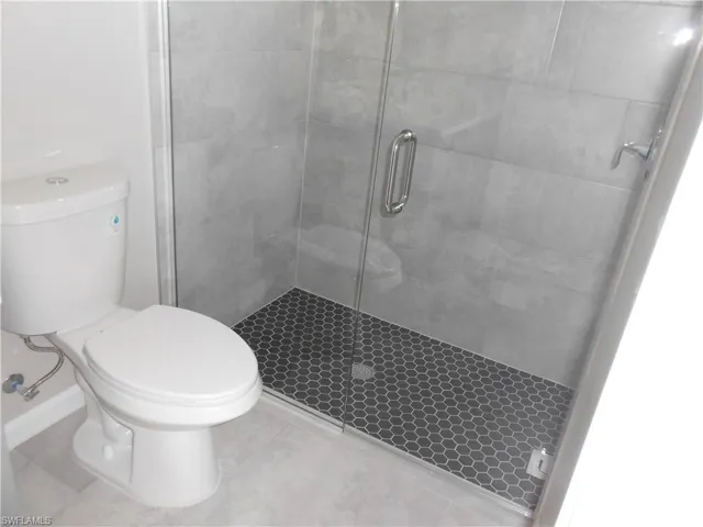 Full bathroom featuring a stall shower and toilet
