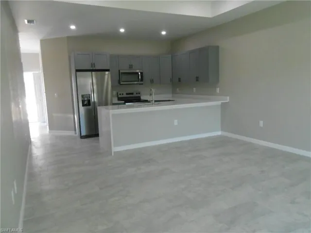 Kitchen featuring stainless steel appliances, gray cabinets, a peninsula, recessed lighting, and open floor plan