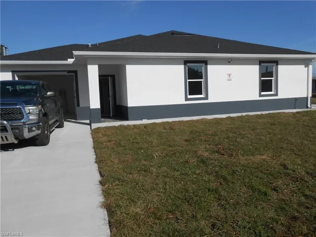 View of side of property with a yard, driveway, and stucco siding