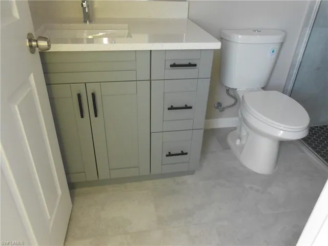 Bathroom with vanity, light tile patterned floors, and a stall shower